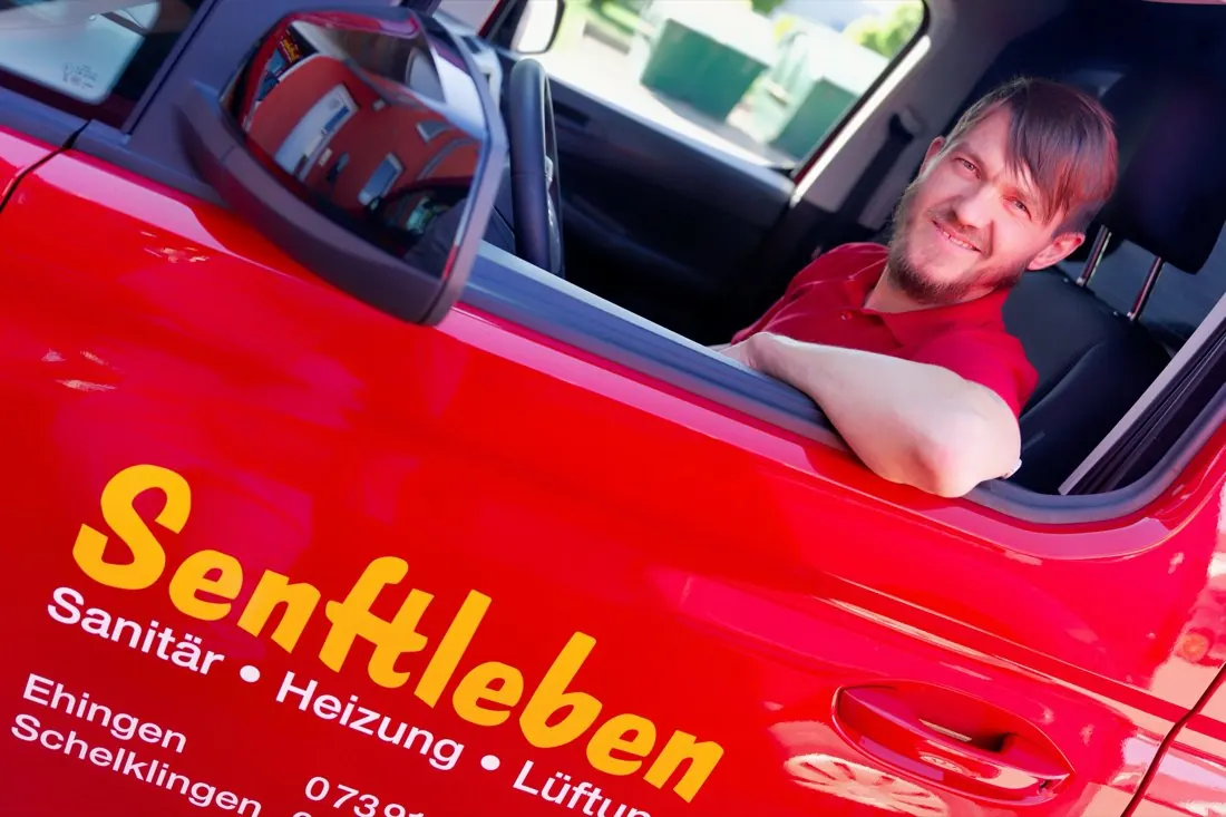 Benjamin Senftleben schaut aus dem Fenster des roten Firmenwagens von Senftleben Haustechnik