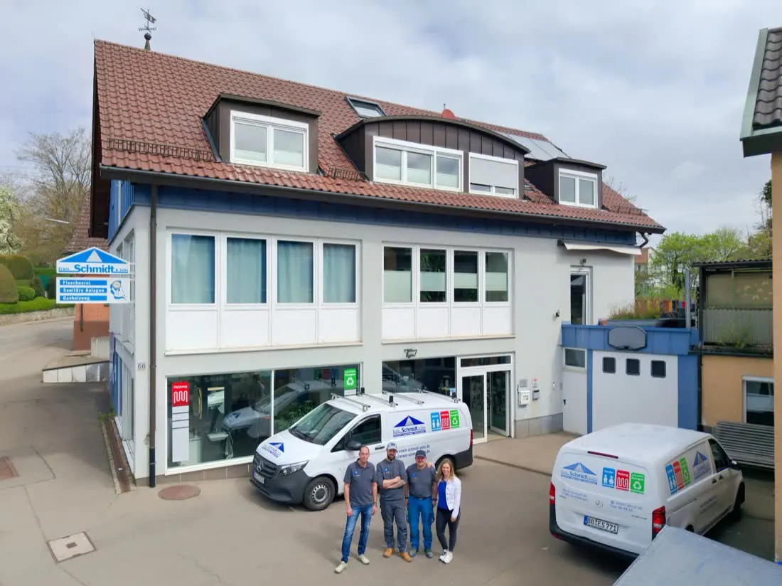 Betriebsgebäude eines SHK-Betriebs mit zwei Firmenwagen und dem Team davor
