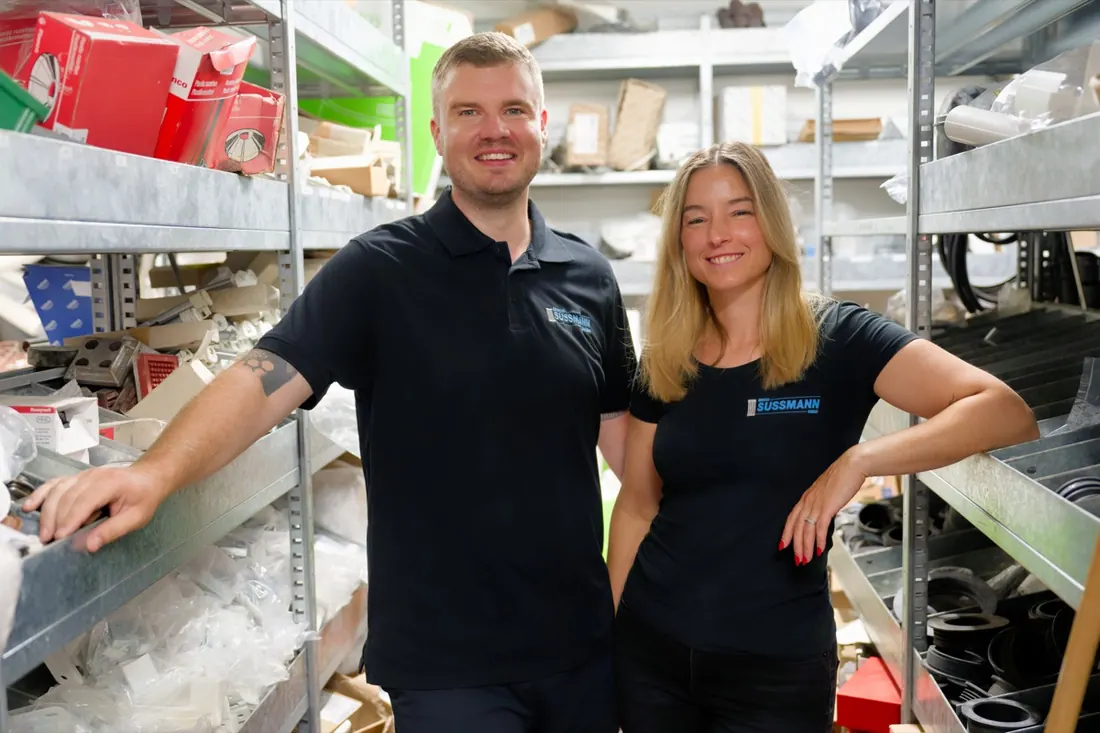 Patrick Wähnl und Mirjana am Empfang der Erich Sussmann GmbH, dahinter das Firmenlogo an einer Pflanzenwand